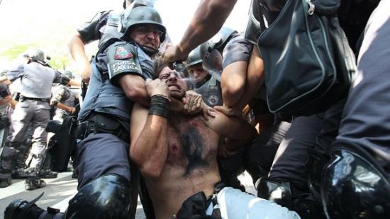 Répression policière le 12 juin lors du match d'ouverture. Un manifestant contre la Coupe, immobilisé, reçoit un jet de spray au poivre dans les yeux